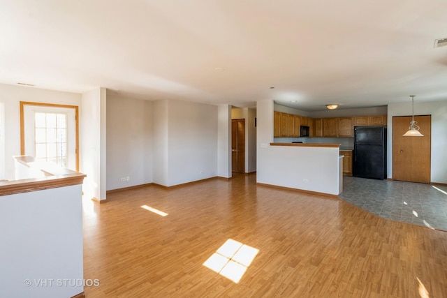 unfurnished living room featuring visible vents, baseboards, and light wood-style floors