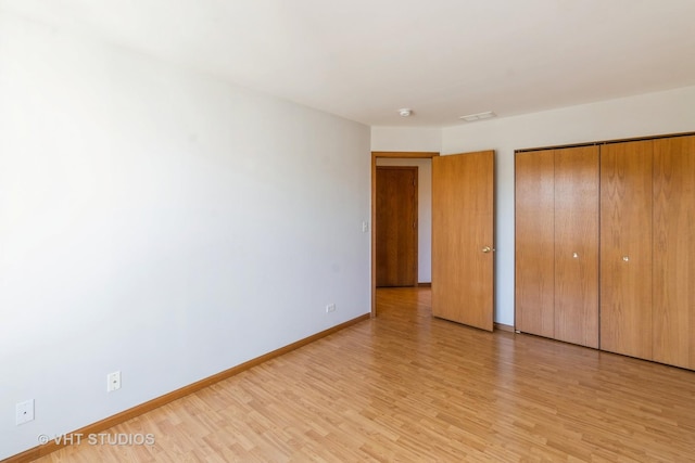 unfurnished bedroom featuring baseboards, visible vents, light wood finished floors, and a closet