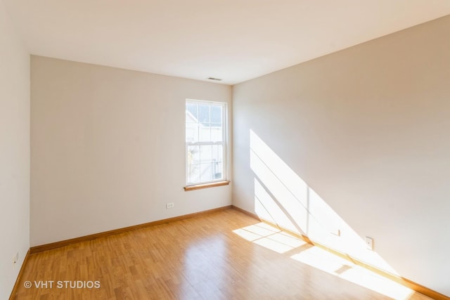 unfurnished room with baseboards, light wood-style floors, and visible vents