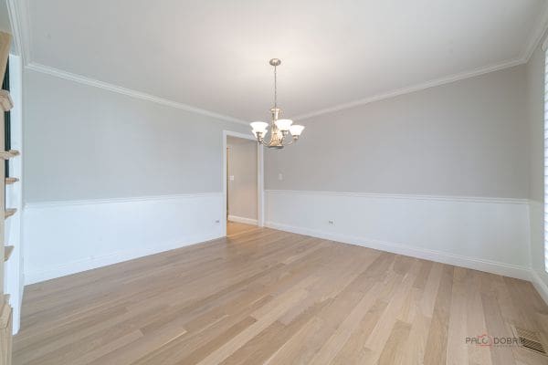 empty room featuring baseboards, light wood-style floors, a notable chandelier, and crown molding
