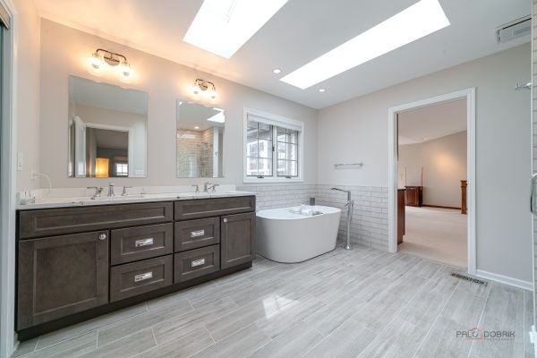 bathroom featuring a skylight, a freestanding tub, a sink, and double vanity
