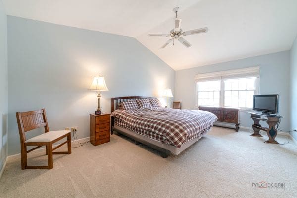 carpeted bedroom featuring vaulted ceiling, baseboards, and a ceiling fan