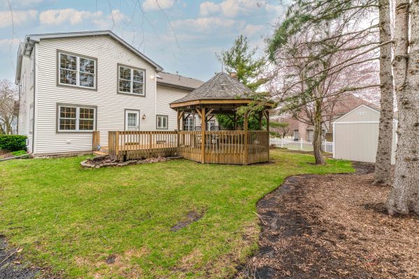 rear view of house with a lawn, a storage unit, a gazebo, and a wooden deck