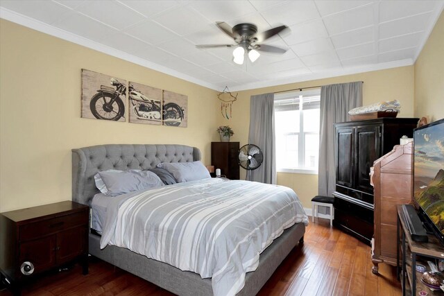 bedroom with crown molding, dark wood-type flooring, and a ceiling fan