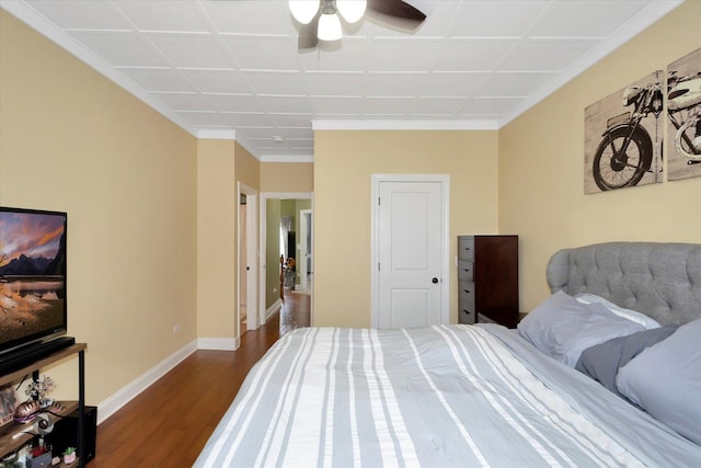 bedroom with dark wood-style flooring, ornamental molding, and baseboards