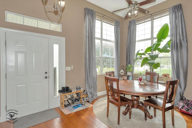 dining room with a healthy amount of sunlight, light wood-type flooring, and ceiling fan with notable chandelier