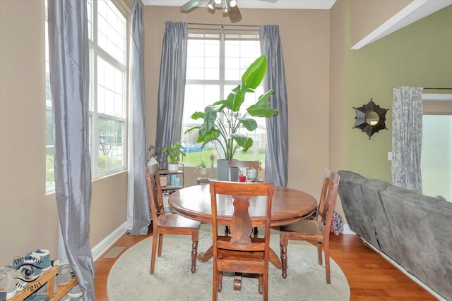 dining space with baseboards, visible vents, ceiling fan, and wood finished floors