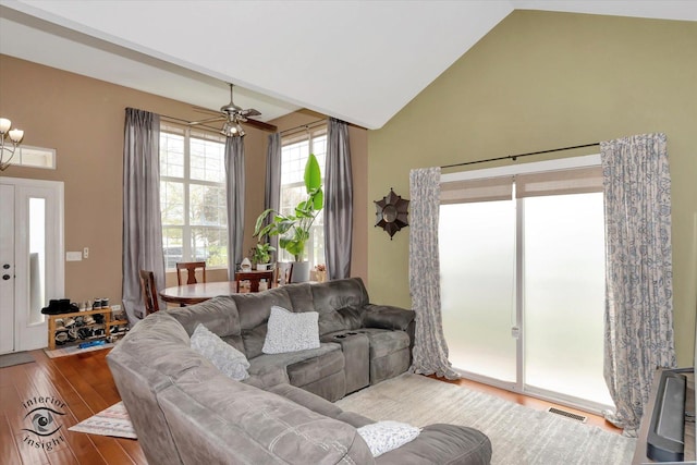 living area with visible vents, high vaulted ceiling, and wood finished floors