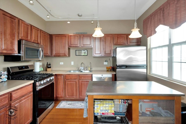 kitchen featuring light wood finished floors, light countertops, appliances with stainless steel finishes, and a sink