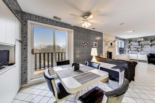 dining area with wallpapered walls, visible vents, a ceiling fan, and light tile patterned floors