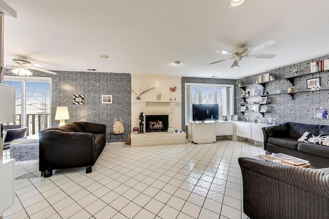 living area featuring a ceiling fan, visible vents, a fireplace with raised hearth, and light tile patterned floors
