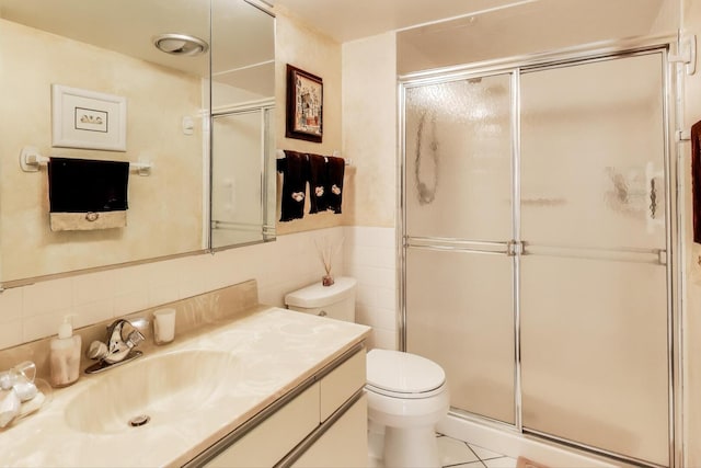 bathroom featuring tile patterned floors, toilet, tile walls, a stall shower, and vanity
