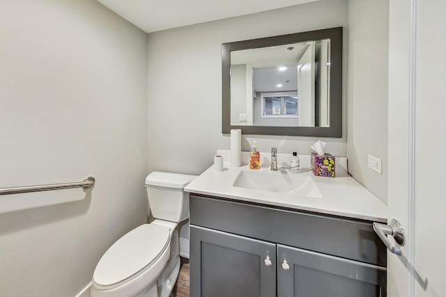 half bath with baseboards, toilet, vanity, and wood finished floors