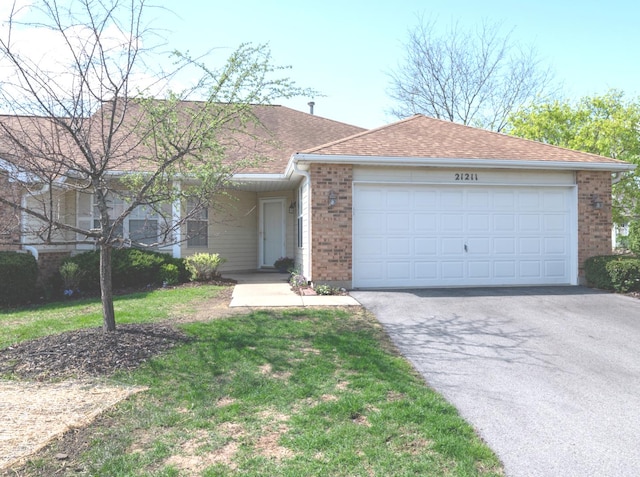 ranch-style house with a front yard, roof with shingles, brick siding, an attached garage, and driveway