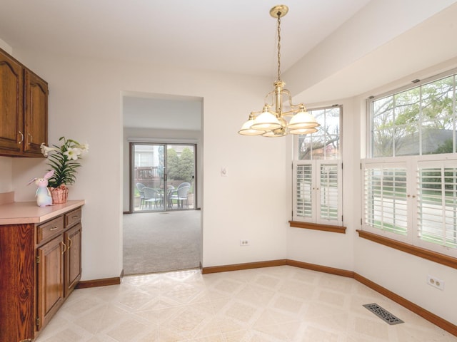 unfurnished dining area featuring visible vents, baseboards, light colored carpet, and an inviting chandelier