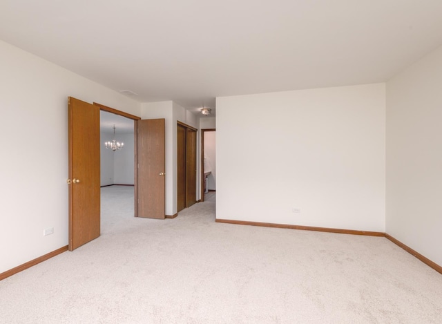 carpeted empty room with baseboards and a notable chandelier