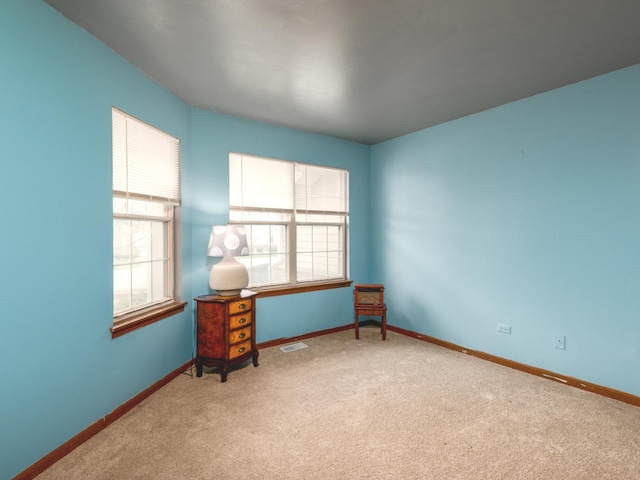 spare room with visible vents, carpet flooring, and a wealth of natural light
