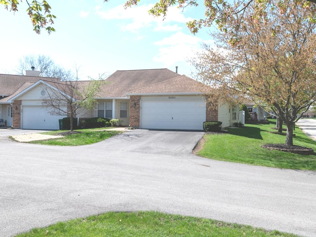 ranch-style home featuring brick siding, aphalt driveway, a front lawn, and an attached garage