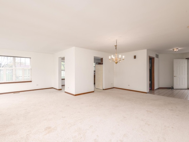 empty room with an inviting chandelier, baseboards, visible vents, and light colored carpet