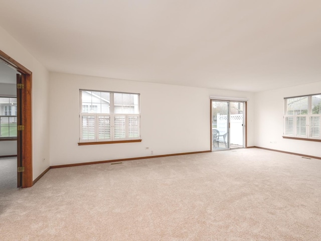 spare room with baseboards, visible vents, and light carpet