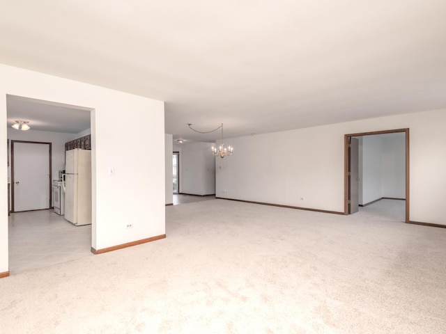 empty room featuring baseboards, light carpet, and a notable chandelier