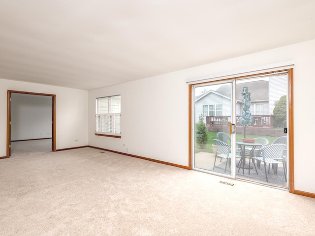 spare room with baseboards, light carpet, and visible vents