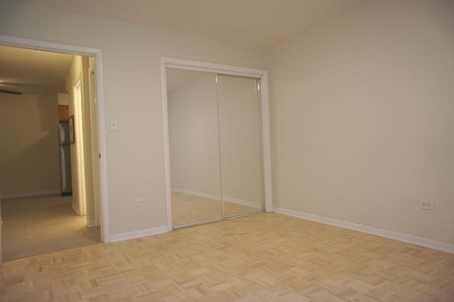 unfurnished bedroom featuring a closet, baseboards, and freestanding refrigerator