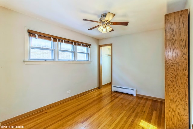 spare room with a baseboard heating unit, light wood-type flooring, a ceiling fan, and baseboards