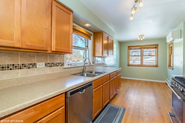 kitchen featuring stainless steel appliances, a sink, light wood-type flooring, baseboards, and a wall mounted air conditioner