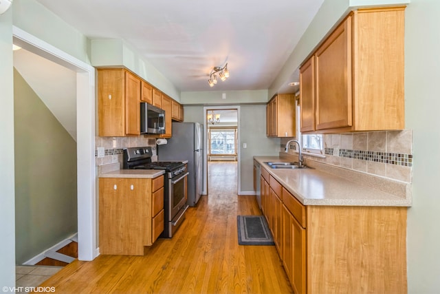 kitchen with a sink, decorative backsplash, light wood-style floors, stainless steel appliances, and light countertops