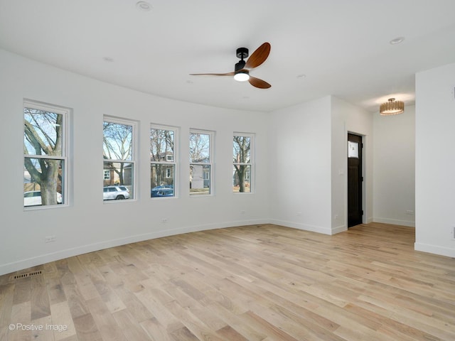 empty room featuring visible vents, light wood finished floors, baseboards, and a ceiling fan
