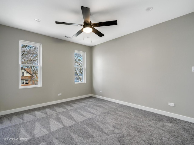 unfurnished room with carpet floors, visible vents, a ceiling fan, and baseboards