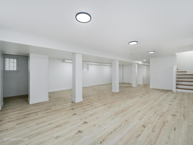 basement featuring wood finished floors, baseboards, and stairway