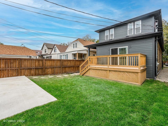 rear view of house featuring a lawn, fence, a deck, and a patio