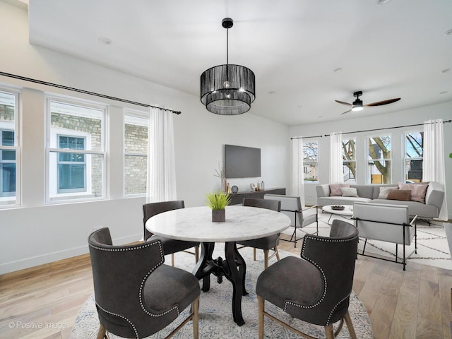 dining space with ceiling fan, baseboards, and light wood-style flooring