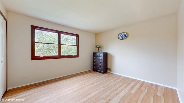 unfurnished room with baseboards and light wood-style flooring