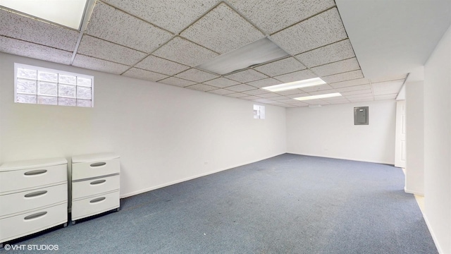 basement with a paneled ceiling, dark carpet, baseboards, and electric panel