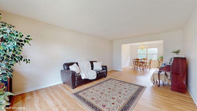 living area with light wood finished floors, a chandelier, and baseboards