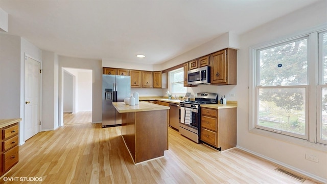 kitchen with light wood-style flooring, brown cabinetry, visible vents, light countertops, and appliances with stainless steel finishes