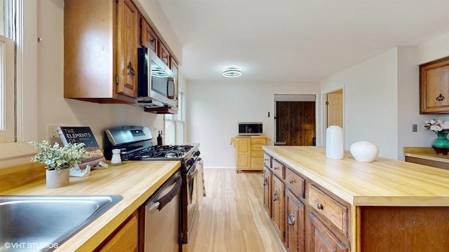 kitchen with appliances with stainless steel finishes, brown cabinets, butcher block counters, and light wood-style floors