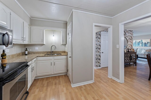 kitchen featuring white cabinets, light stone counters, stainless steel appliances, a sink, and light wood-style flooring