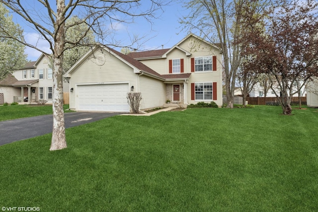 traditional-style home with a garage, a front lawn, aphalt driveway, and fence