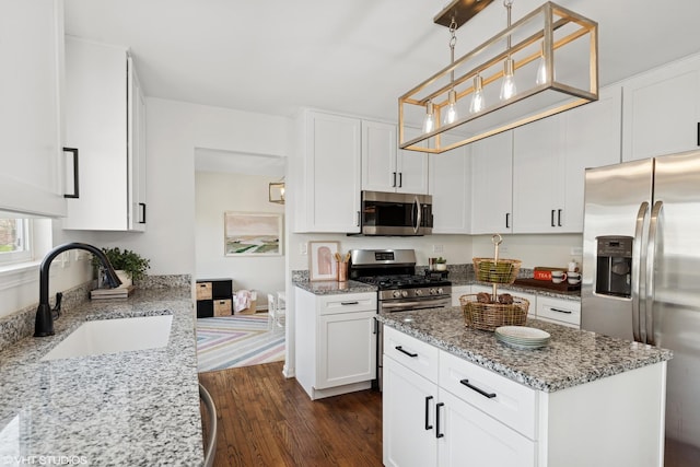 kitchen featuring dark wood-style flooring, light stone countertops, a sink, white cabinets, and stainless steel appliances