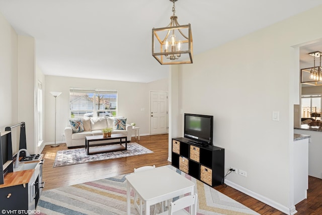 living room with an inviting chandelier, baseboards, and wood finished floors
