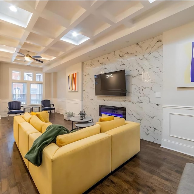 living area featuring dark wood-style floors, beam ceiling, coffered ceiling, a ceiling fan, and a decorative wall