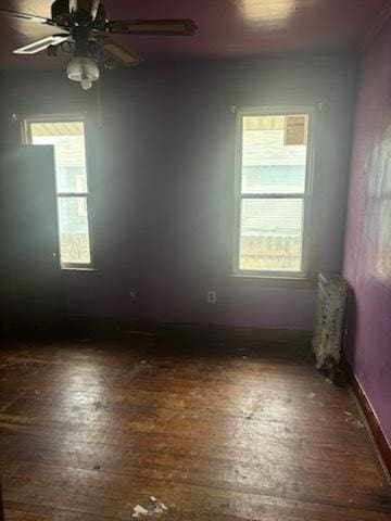 unfurnished room featuring ceiling fan, a wealth of natural light, hardwood / wood-style floors, and baseboards