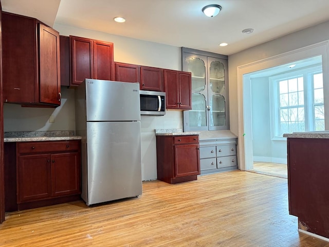 310 Elk St, Galena, IL 61036 - kitchen with stainless steel appliances, dark brown cabinets, recessed lighting, light wood-style floors, and glass insert cabinets