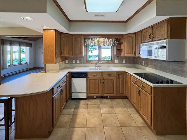 kitchen with a baseboard radiator, a sink, decorative backsplash, white appliances, and visible vents