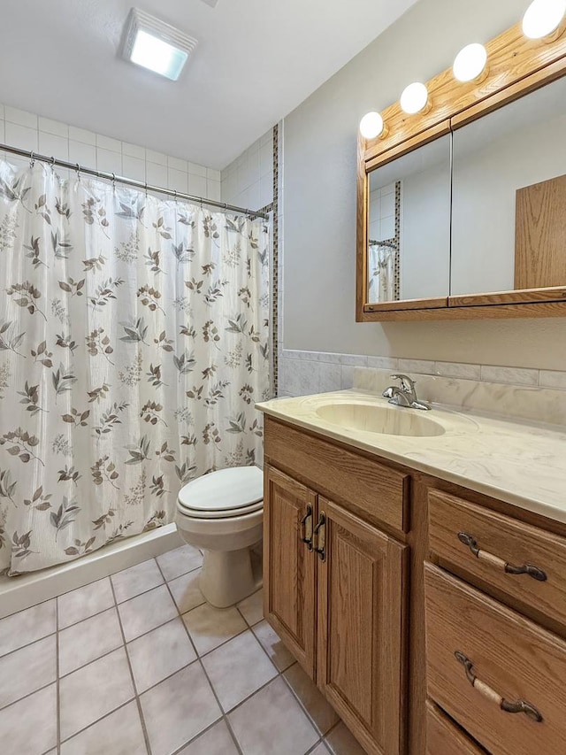 bathroom with curtained shower, vanity, tile patterned flooring, and toilet