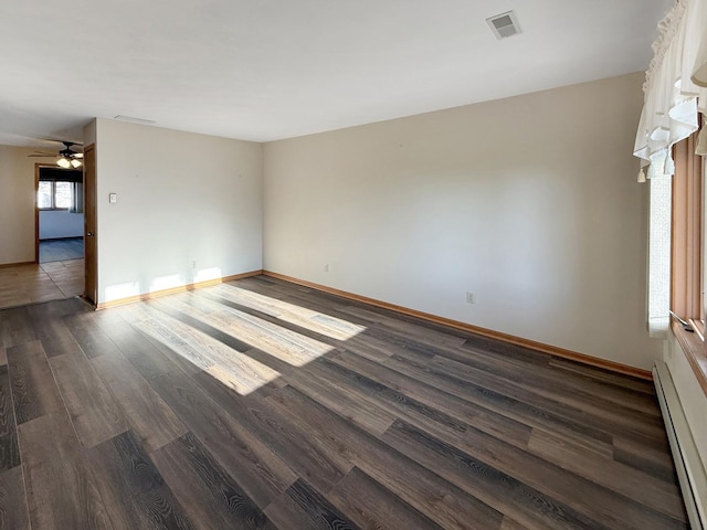 unfurnished room with visible vents, dark wood-style flooring, baseboards, a baseboard radiator, and ceiling fan